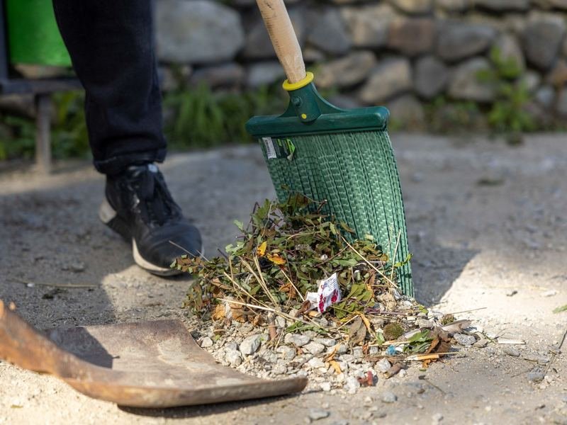 Worker raking autumn leaves